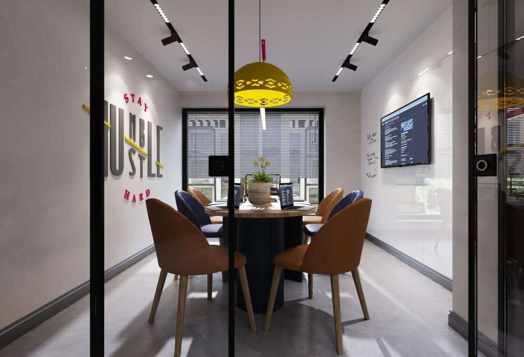 Glass-walled meeting pod with orange chairs and graphic wall