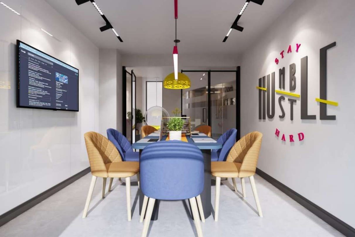 Co-working huddle room with pastel seating and 'Stay Hustle Hard' graphic wall