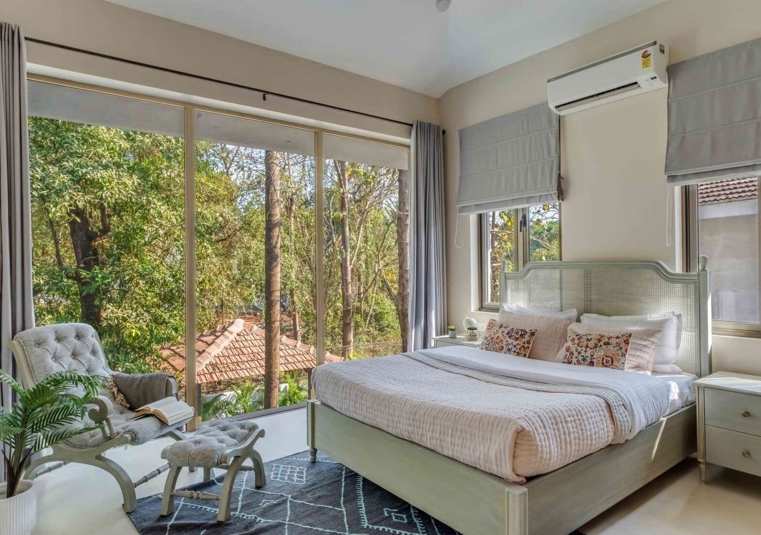 Bedroom with tufted armchair and balcony overlooking treetops