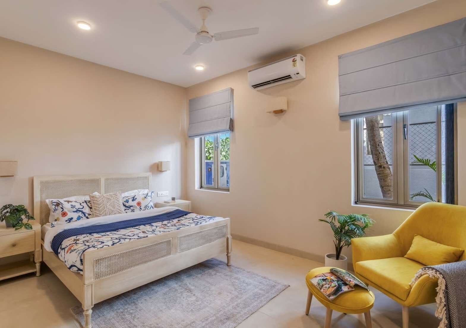 Bedroom in blue and white block-print linens with a yellow accent chair